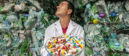 Naukowiec trzymama misę z lekami, w tle góry z plastikowych butelek