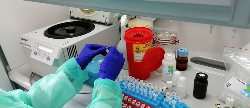 Medyk wykonuje badania w laboratorium (widać dłonie w rękawiczkach)