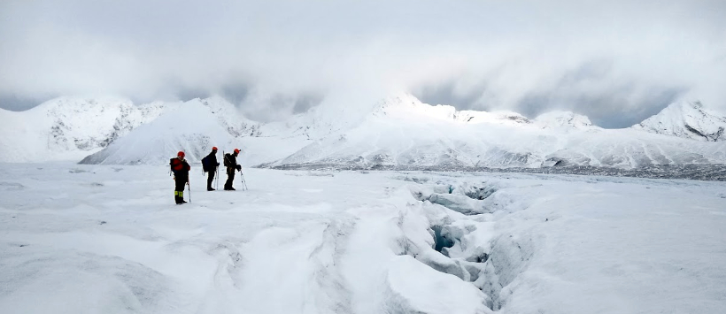 Trzech członków wyprawy polarnej na Horsund (Spitsbergen) stoi na skraju szczeliny w lodowcu