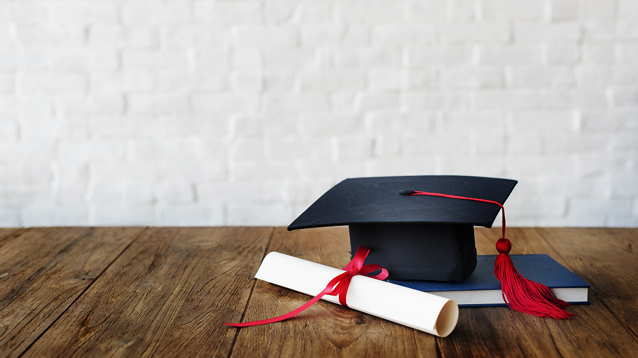 Studencka czapka i dyplom leżą na stole