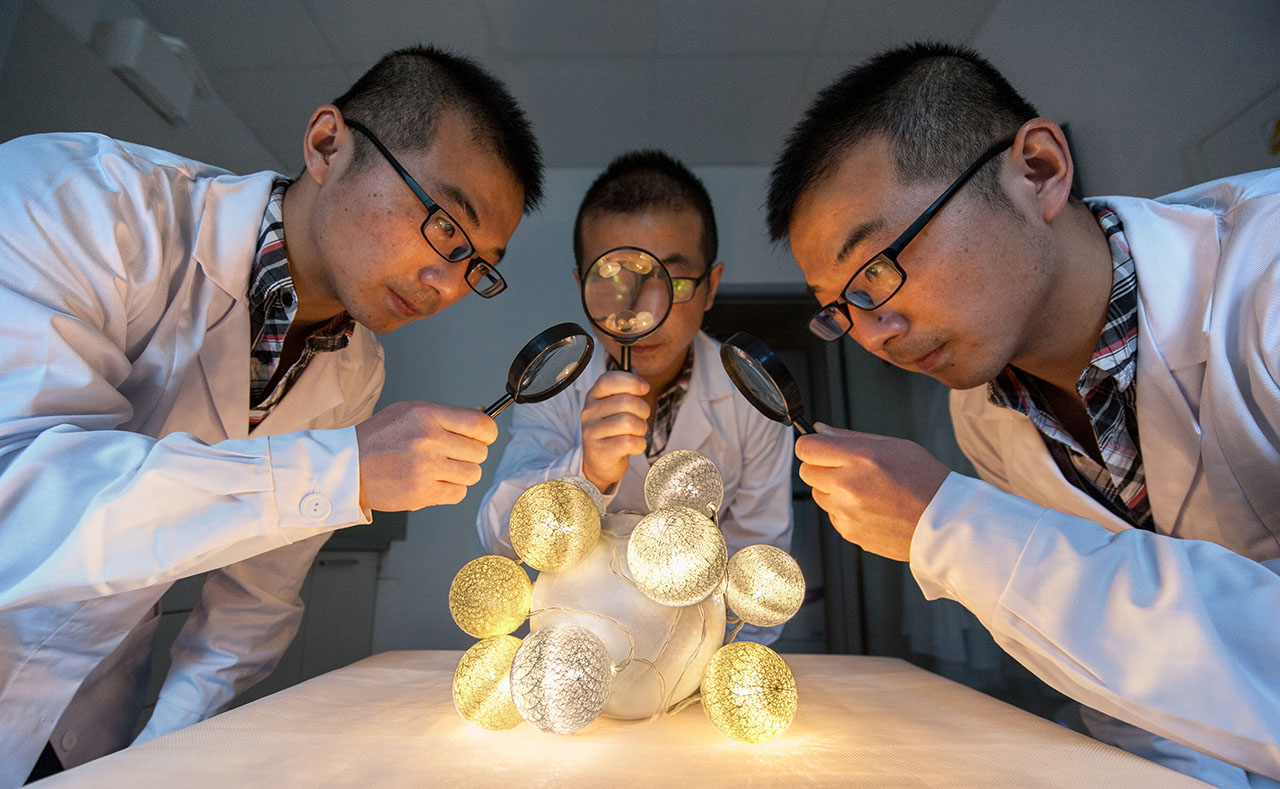 Trójka identycznych naukowców z lupami przy twarzach ogląda obiekt symbolizujący cząsteczkę chemiczną
