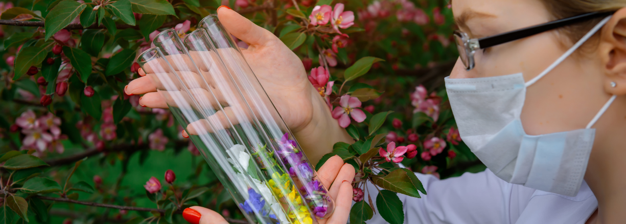 Młoda naukowczyni trzyma w rękach próbki zawierające kwiaty rożnych gatunków roślin