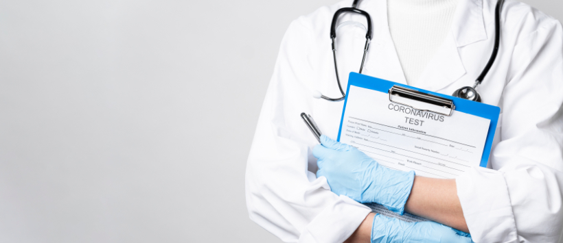 Lekarka w kitlu i ze stetoskopem trzyma dokument z napisem "test na obecność koronawirusa"
