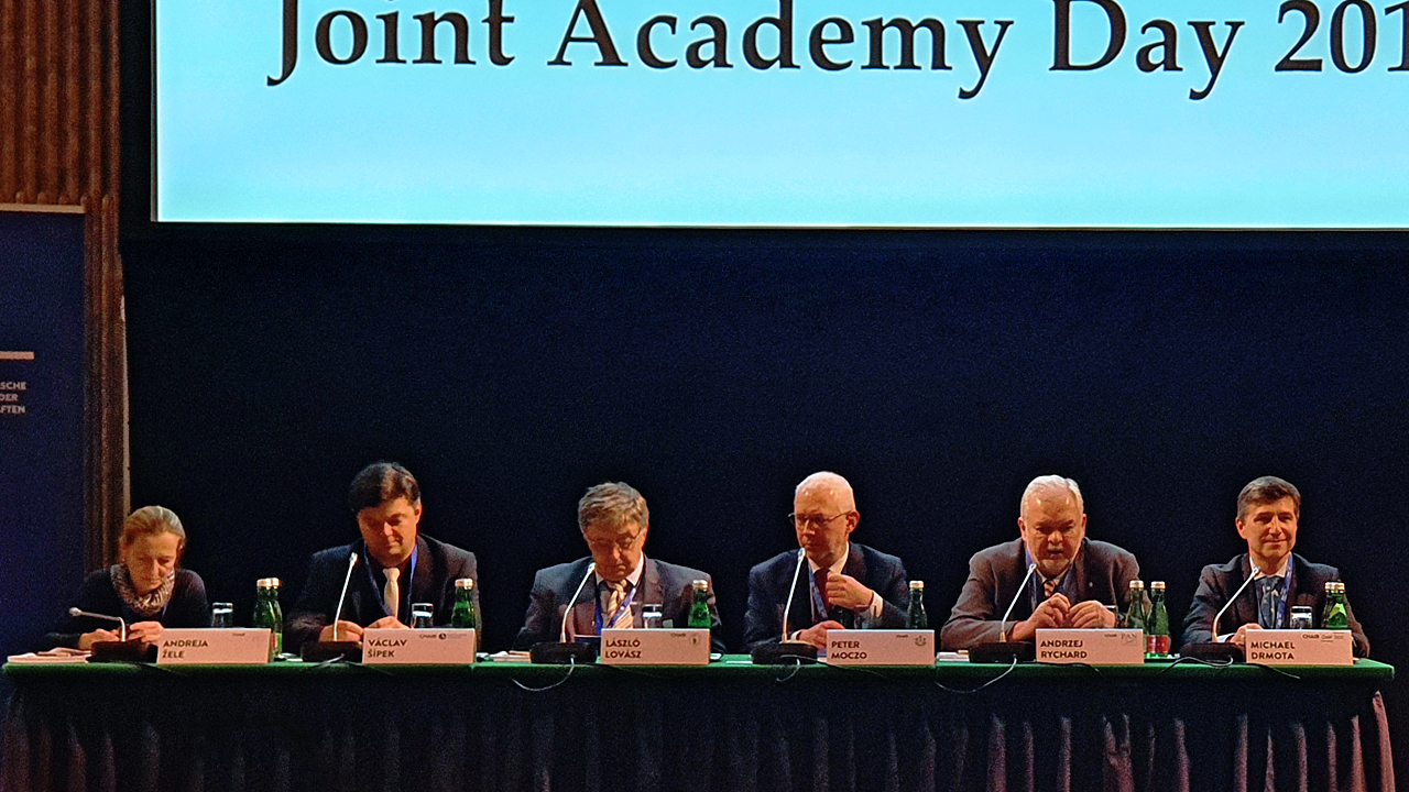 Sześciu naukowców siedzi za stołem prezydialnym, przy mównicy stoi moderator dyskusji
