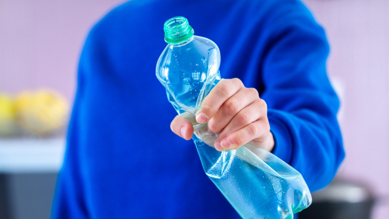 Męska ręka zgniata plastikową butelkę