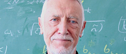 Prof. Jerzy Kijowski stoi przed tablicą zapisaną wzorami fizycznymi
